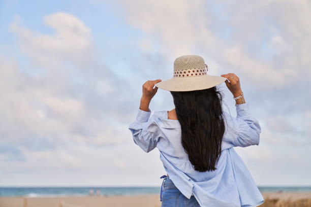 istock A woman wearing a straw hat stands on a beach 2157088299