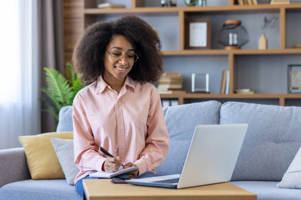 istock Woman working remotely on laptop in living room, taking notes 2157090020
