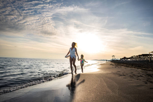 istock Mother and daughter running on the beach 2157090086
