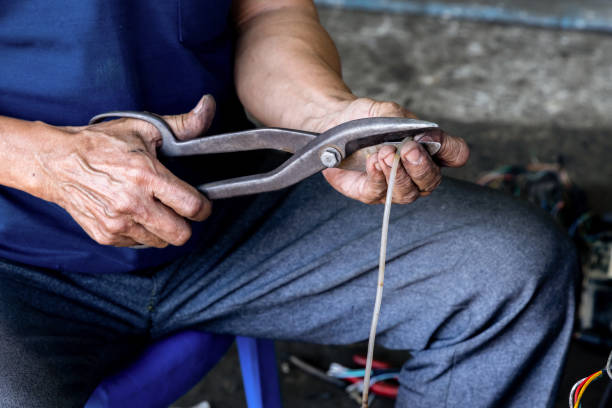istock Photo of hands holding pliers in their hands while cutting a small plastic pipe. 2157090507