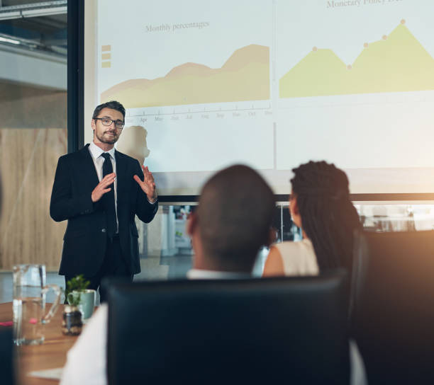 istock Business people, presentation and graphs for finance, projection and share information in meeting. Group, employees or speaker with screen, charts or revenue for startup, brainstorming or cooperation 2157091236