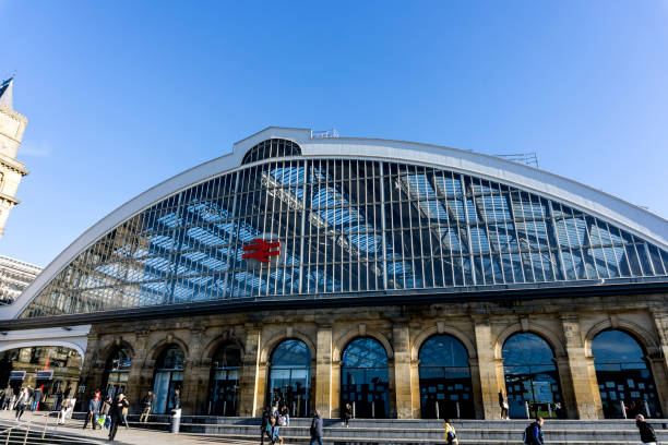 The front of Liverpool Lime Street Railway Station with travellers outside on a sunny day, the oldest operating grand terminus mainline station in the world