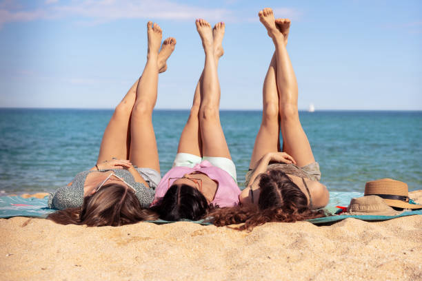 istock Three beautiful girls on the beach lying on the sand 2157100716