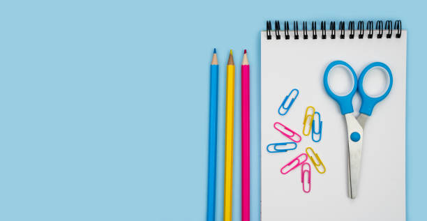 Notebook, scissors and pencils on a blue background. Back to school. Banner. Flatlay. Top view. Copy space.