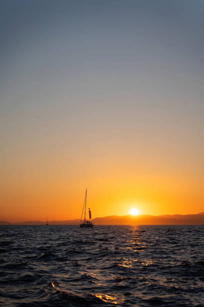 A sailboat is sailing along the sea during sunset