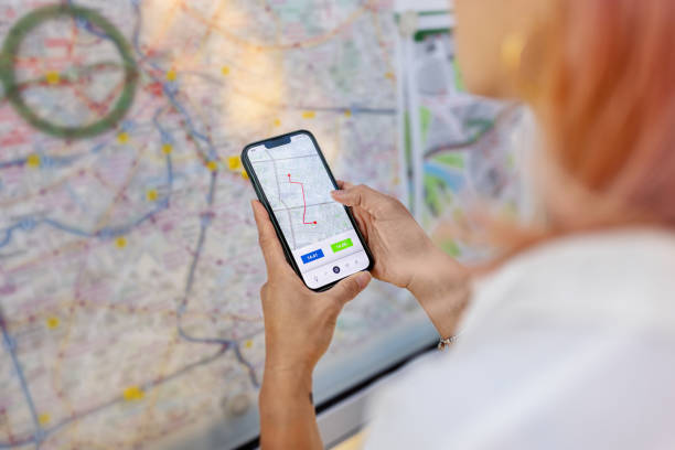 istock Woman commuter with mobile phone looking at the train network map on platform 2157101122