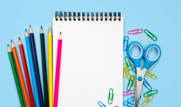 istock A white blank notebook and colorful school stationery on a blue background. Mockup. Flatlay. Top view. Copy space. 2157101247