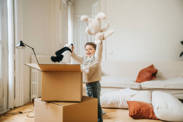 istock Little boy opening boxes in his new house 2157104171