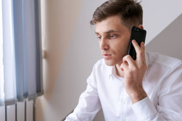 istock A man is talking on his cell phone while sitting at a desk 2157107098