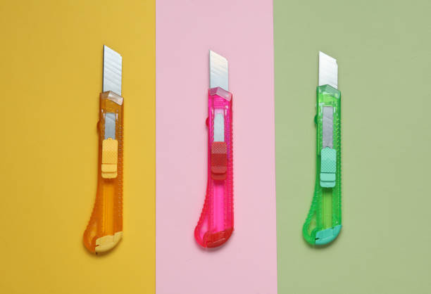 Plastic colored stationery knives for cutting paper on pastel background