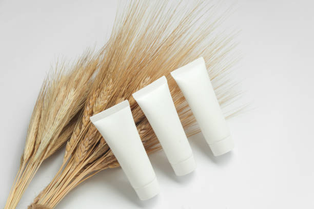 White cream tubes with wheat spikelets on white background. Natural cosmetics concept. Mockup for design