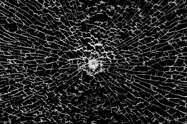 istock Texture of broken tempered glass with a bullet hole and diverging cracks on a black background. Design element. 2157110869