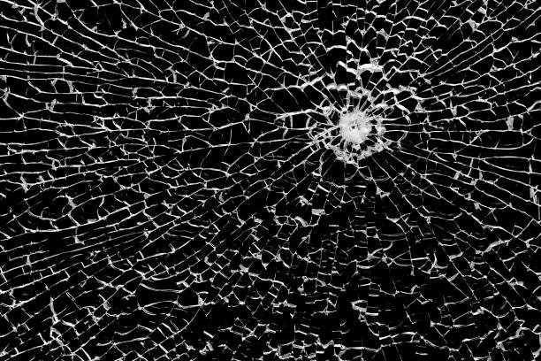 istock Texture of broken tempered glass with a bullet hole and diverging cracks on a black background. Design element. 2157110878