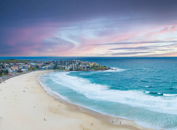 Capture the essence of summer with an aerial view of people relaxing on Bondi Beach, Sydney, under a dramatic afternoon sky, enjoying the sun and surf.