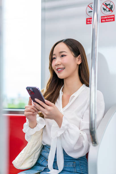 istock Asian woman sitting on a metro skytrain, using her phone and looking away 2157112943