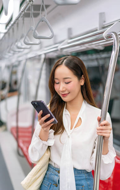 istock Asian Woman Using Phone While Standing and Commuting on a Metro Skytrain 2157113377
