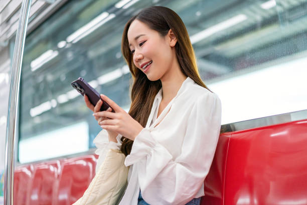 istock Asian woman sitting and using phone while commuting on a metro skytrain 2157113404