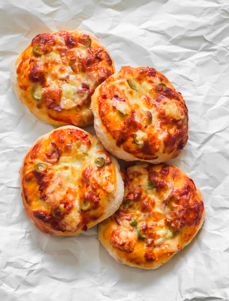 Mini pizza with ham, olives and mozzarella - a delicious snack, tapas on a light background, top view