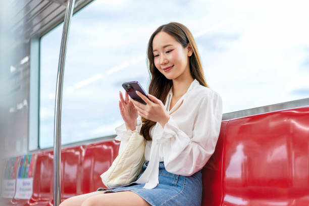 istock Asian woman sitting and using phone while commuting on a metro skytrain 2157113494