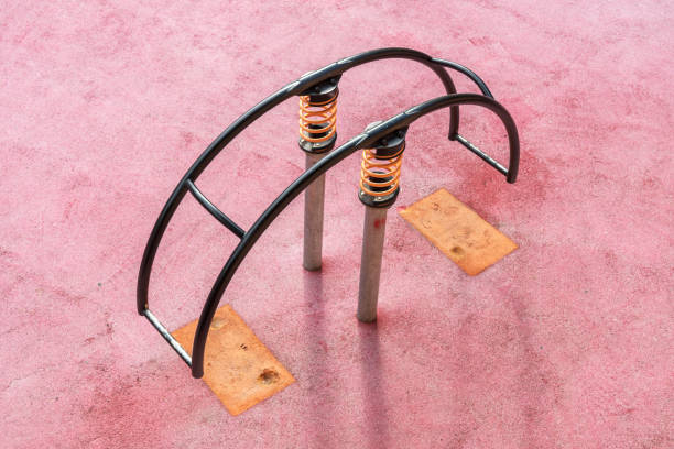 Balancing swing on spring against pink rubber surface on sunny day. Children's swing on a spring.  Children's playground.