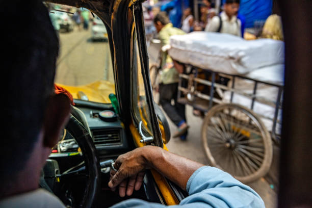 Rear view of taxi driver waiting for worker crossing road while pulling cart in city street of Kolkata
