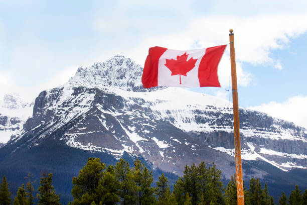 istock Canadian flag blows in the wind below mountains 2157124370