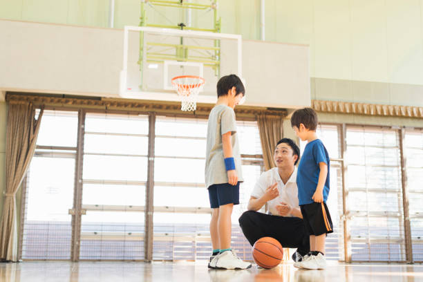 istock Boys practising with their coach on the basketball court. 2157128143