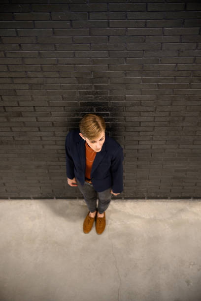 handsome young man in fashionable clothes is sitting on a bench near a metal wall