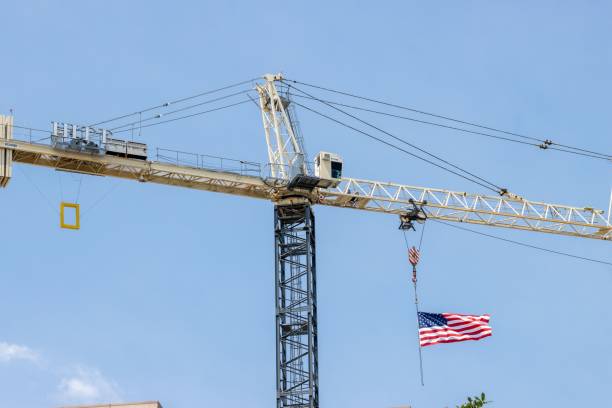 Crawler crane lifting timber in a construction site near an urban area
