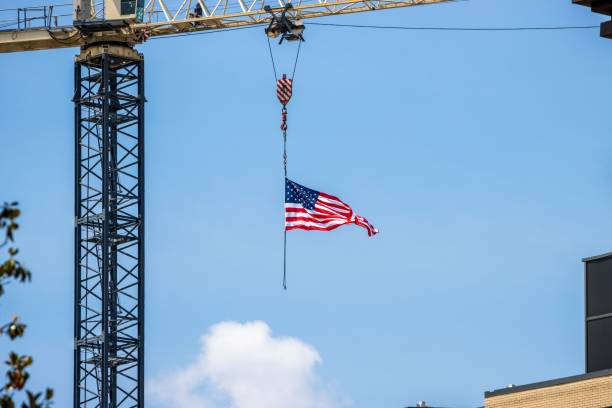 istock American flag hanging from a construction crane against a clear blue sky. 2157129988