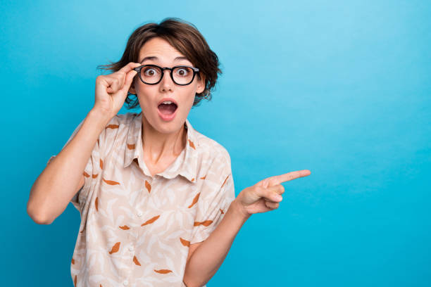Portrait of charming impressed lady arm touch glasses direct finger empty space isolated on blue color background