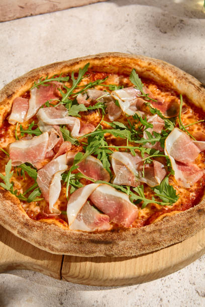 istock Summer Sunlit Pizza with Parma Ham and Arugula on Rustic Background 2157135531