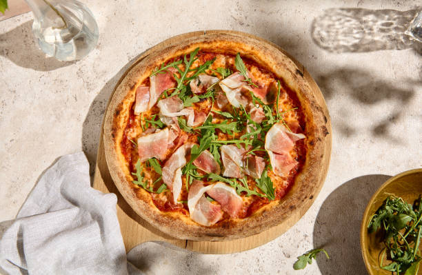 istock Pizza with Parma Ham and Arugula in Summer Sunlight and Shadows 2157135548