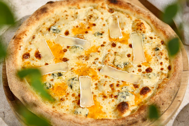 istock Delicious Four Cheese Pizza in Summer Sunlight with Shadows on Rustic Wooden Table 2157135565