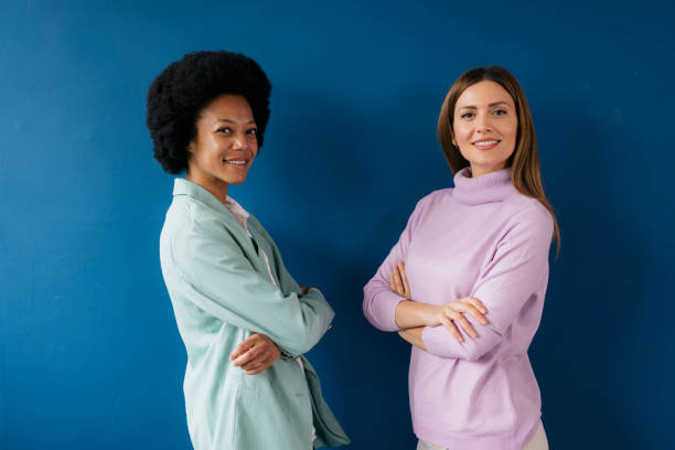istock Two confident businesswomen standing side by side on blue background 2157136380