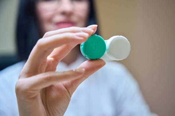 Ophthalmologist holds a container with removable lenses in his hands, a woman has a neat manicure