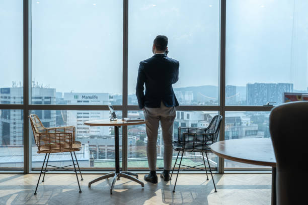istock Asian businessman having phone call looking throw window at office 2157140065