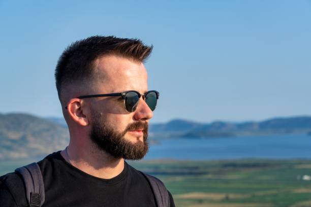 A young Albanian Man wearing sunglasses and looking at the Albanian Riviera Landscape in Sarande.