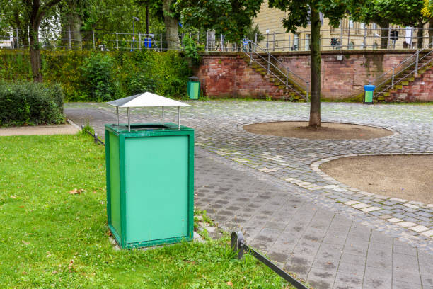 Rubbish bin along a deserted stone path in a public park in a city centre. Copy space. Frankfurt, Germany.