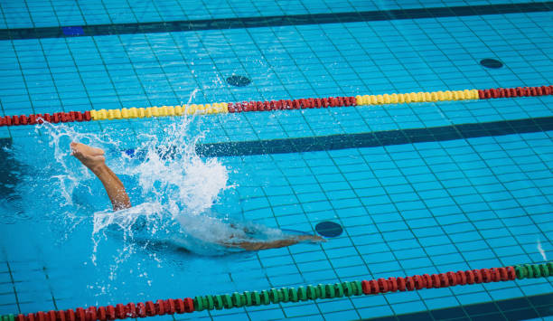 istock Female swimmer preparing and jumping off the starting block 2157146529