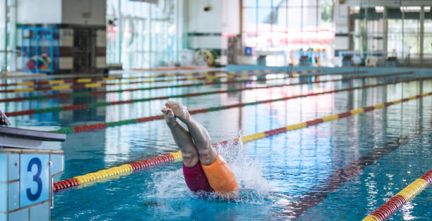 istock Female athlete preparing for a dive start and jumping into the pool 2157147364
