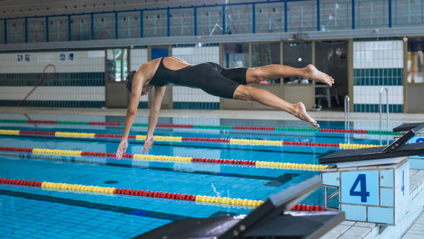 istock Female swimmer preparing and jumping off the starting block 2157147417