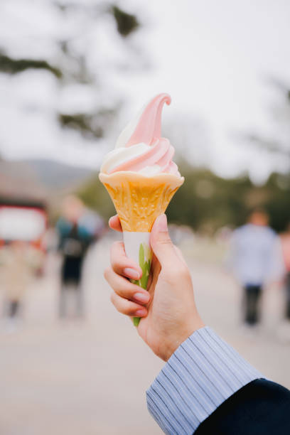 istock A hand holding a pink and white soft serve ice cream cone 2157147563