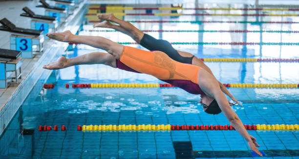 istock Two female swimmers taking the start position and jumping in a pool 2157147830
