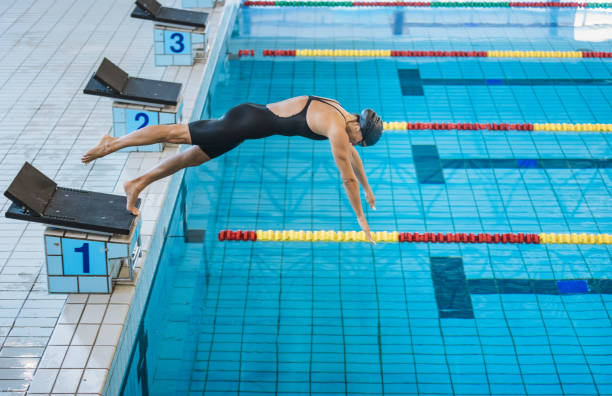 istock Female swimmer preparing and jumping off the starting block 2157147933