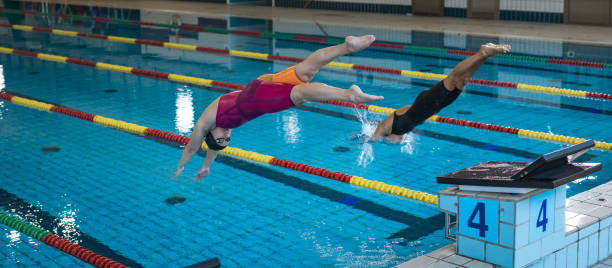 istock Two female swimmers taking the start position and jumping in a pool 2157147984