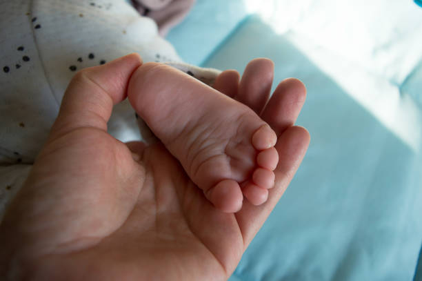 Mother holding newborn foot, concept of family tenderness
