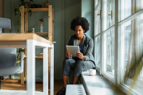 istock Businesswoman on Window Sill with Tablet 2157152284