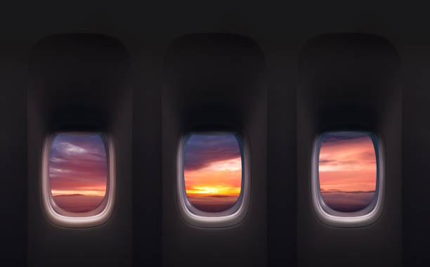 Aerial view through airplane window high above orange sunset sky,Inside Passenger plane POV looking out at beautiful yellow sunrise cloud,Banner transport for Travel,Business Trip,Holiday Vacation