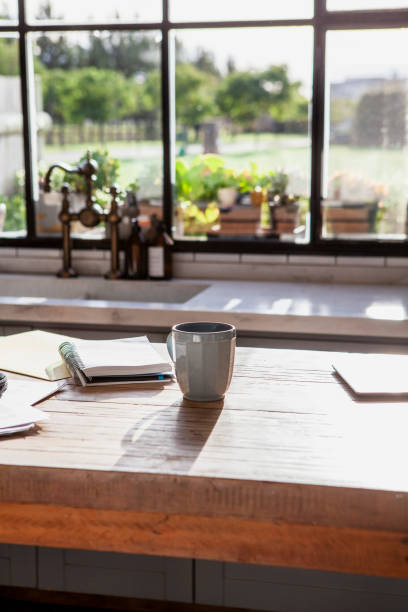 istock Backlit coffee mug on top of table surrounded by copybook and papers inside kitchen 2157153867